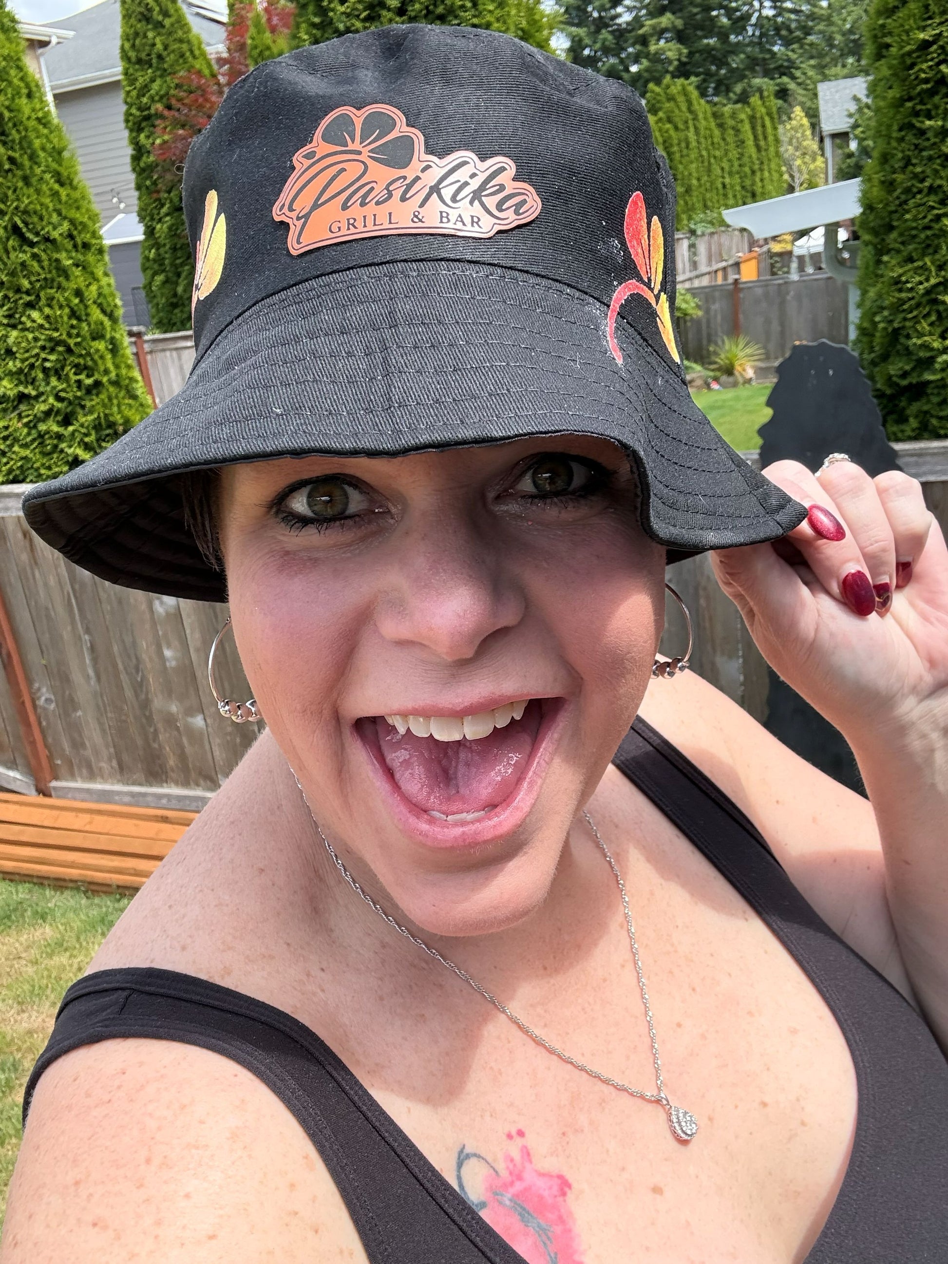 Woman wearing black Pasifika Grill & Bar bucket hat with hibiscus accents