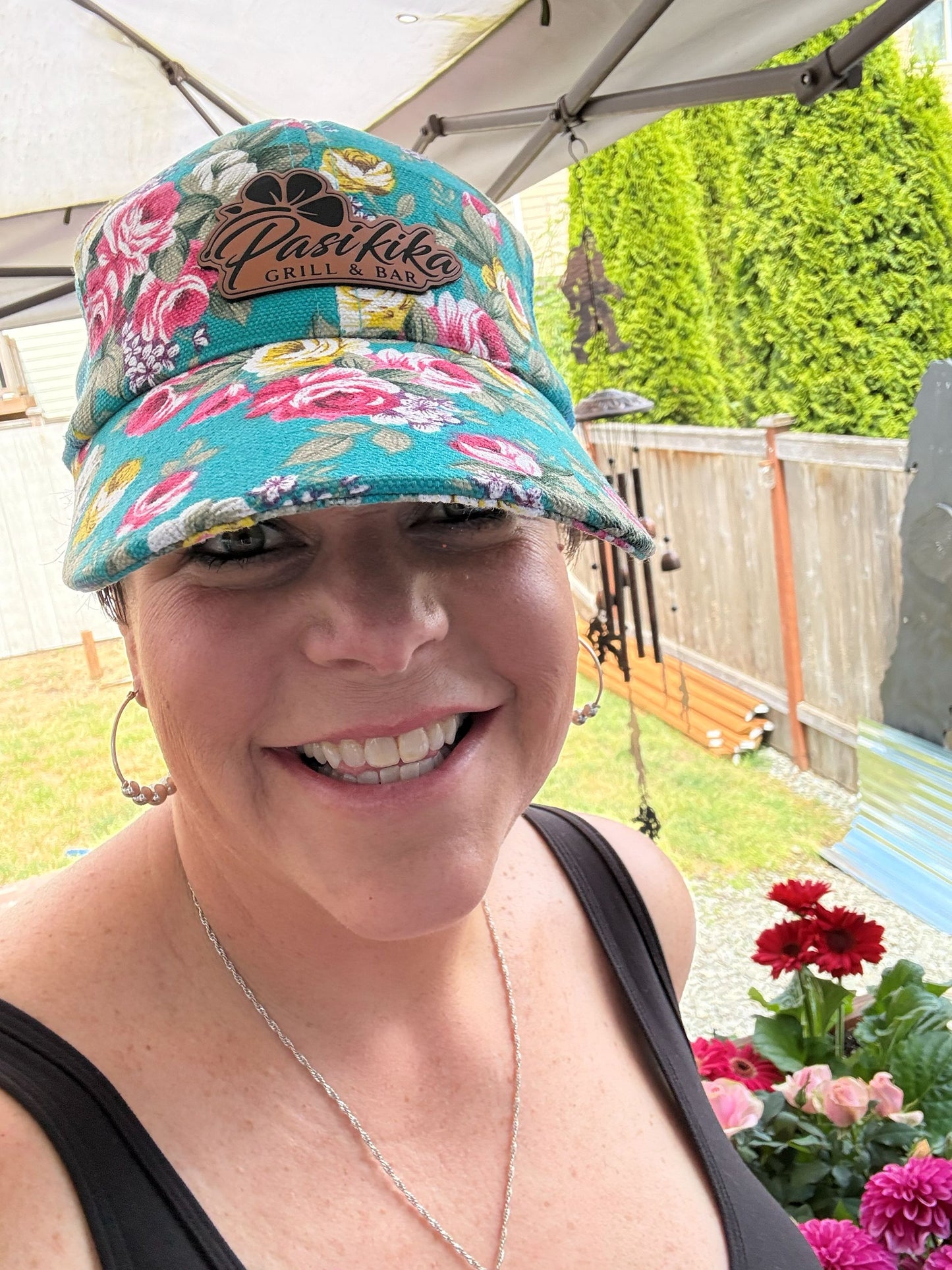 Woman wearing teal floral Pasifika Grill & Bar logo baseball cap